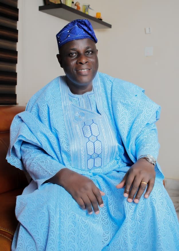 Comrade Ayeola in a seated sky-blue agbada portrait