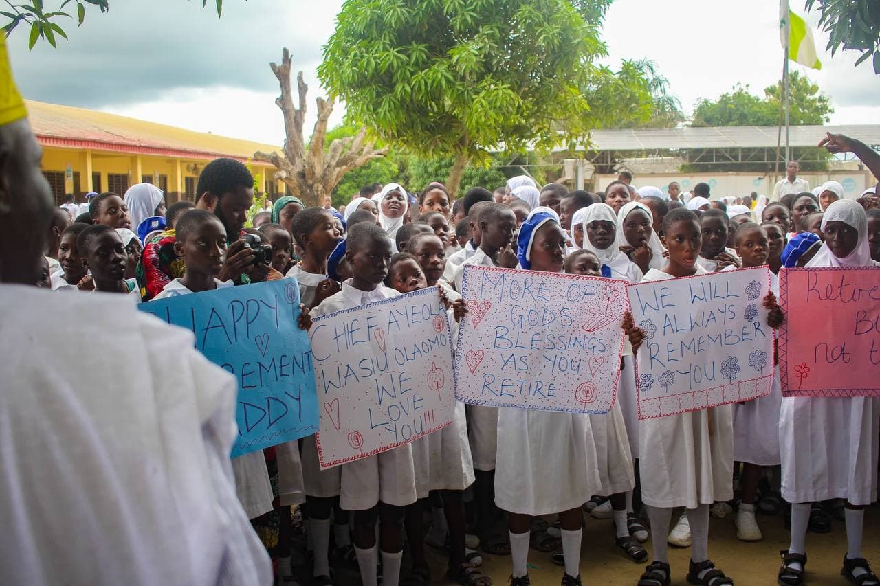 Students at Ibeju Junior High School holding farewell placards for Comrade Ayeola